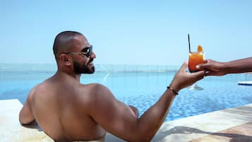 A person sitting by a pool with a drink in hand.