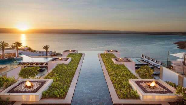 A resort pool area with a sunset view, lounge chairs, and a fire feature. - Hilton Dead Sea Resort & Spa (Sweimeh)