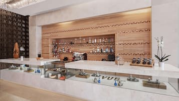 A modern bar area with a wooden wall, shelves with bottles, and a glass display case with tea sets.
