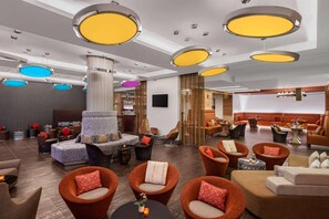 A modern hotel lobby with multiple seating areas, a central column, and ceiling lights. - Hilton Dead Sea Resort & Spa (Sweimeh)