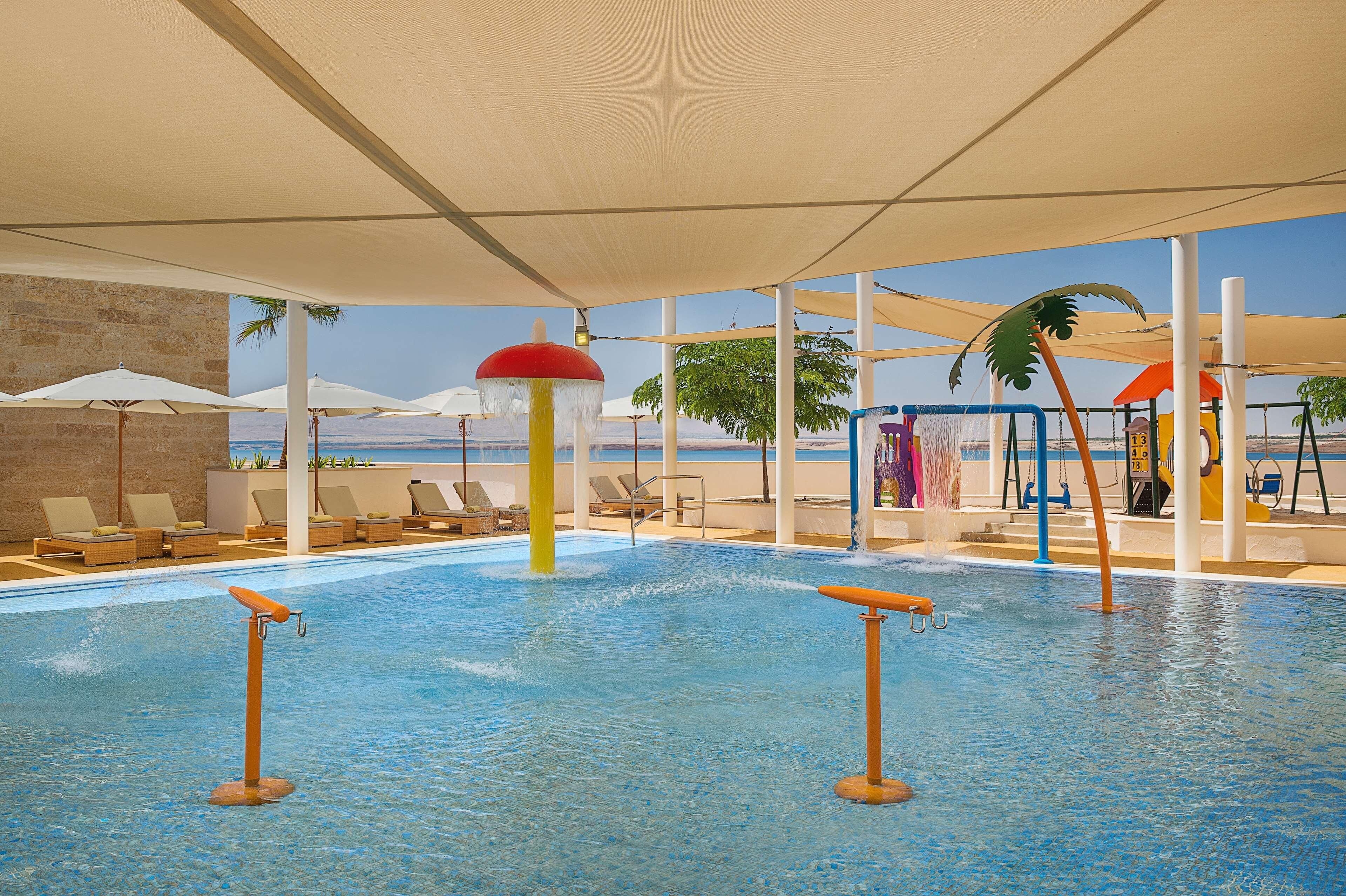 Un espace piscine équipé de chaises longues, de parasols et offrant une vue sur la mer.