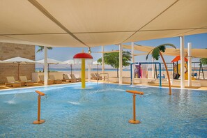 A pool area with lounge chairs, umbrellas, and a view of the sea.