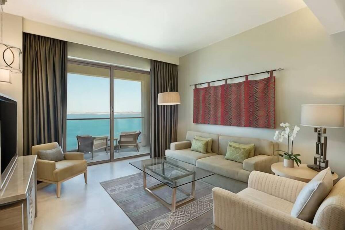 A modern hotel room with a balcony, a sofa set, a coffee table, and a TV.