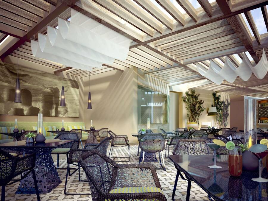 Un interior moderno con techos altos, diseño geométrico en el techo y una variedad de opciones de asiento, incluyendo mesas y sillas.