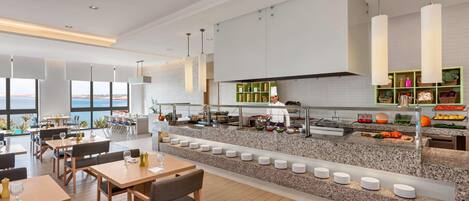 A modern dining area with a buffet, seating arrangements, and a view of the sea.