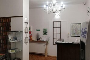 A room with a glass cabinet, a radiator, a desk, a chandelier, and a refrigerator. - Lorf Hostel&Apartments (Krakow)