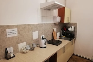 A kitchen with a tiled backsplash, a kettle, a coffee maker, and a sink. - Lorf Hostel&Apartments (Krakow)