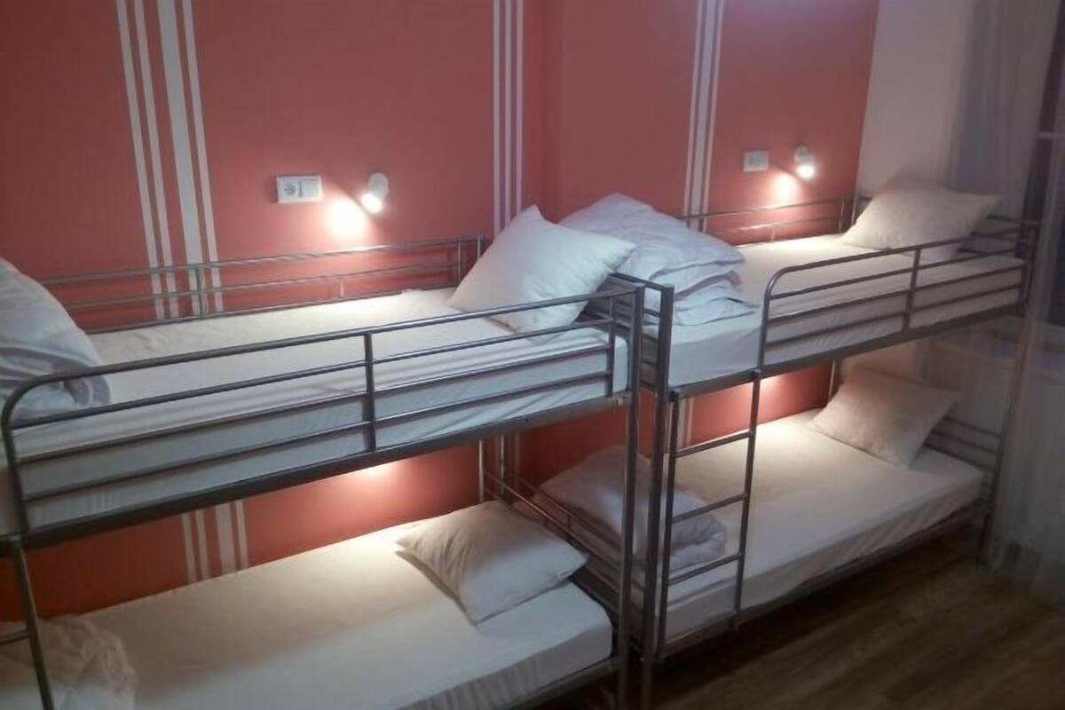A bunk bed room with three levels, each with a mattress and pillows.