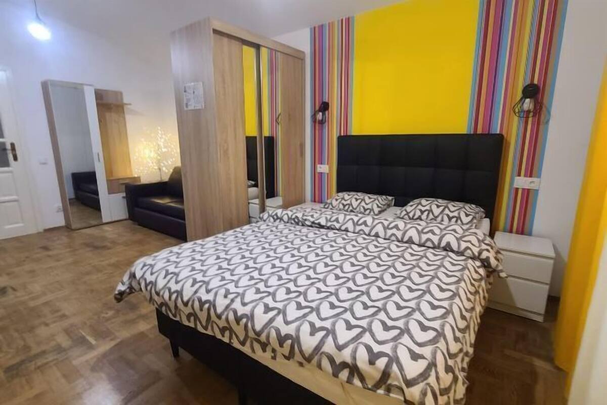 A bedroom with a bed, a wardrobe, a nightstand, and a lamp.