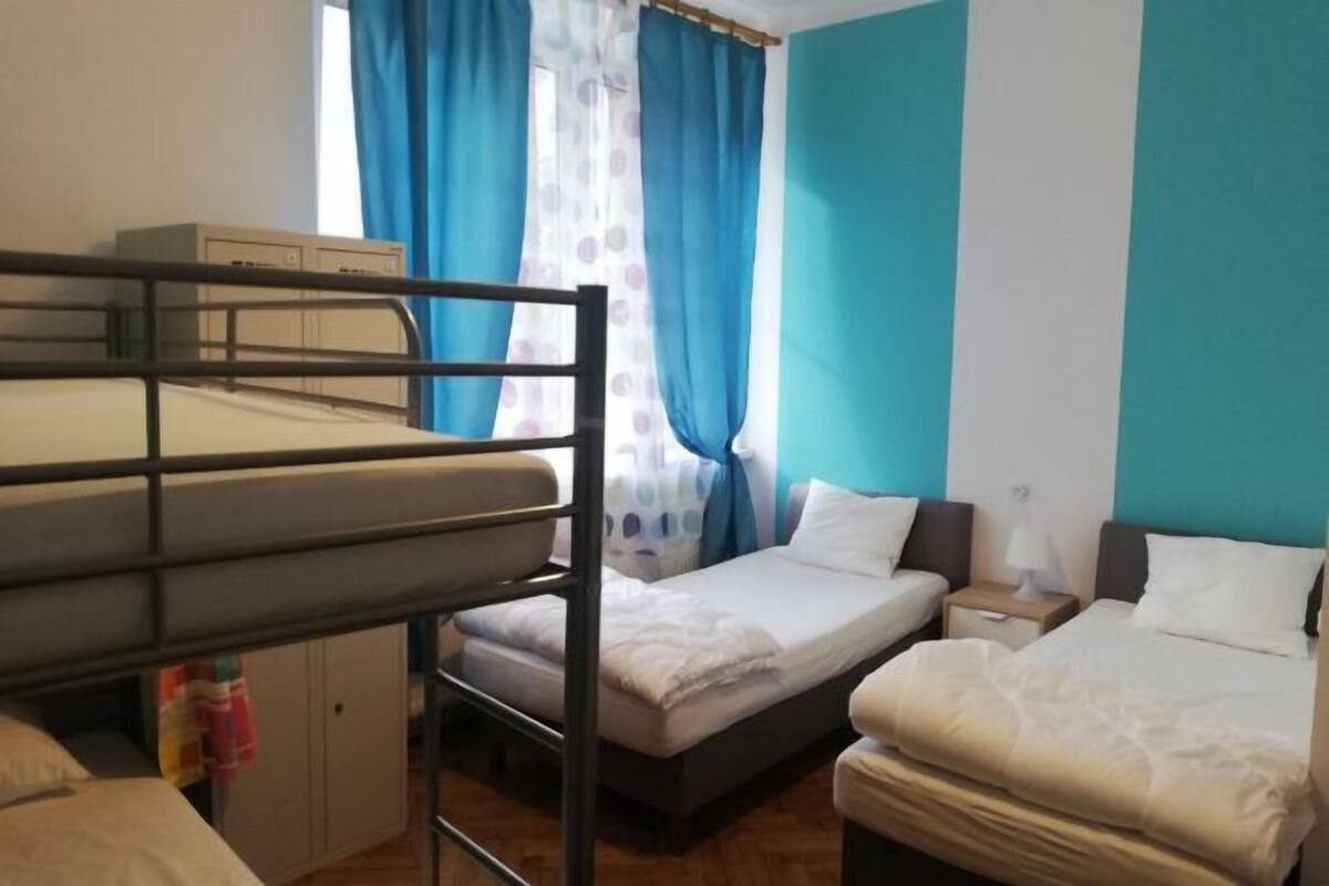 A room with bunk beds, a single bed, a nightstand, and a wardrobe.