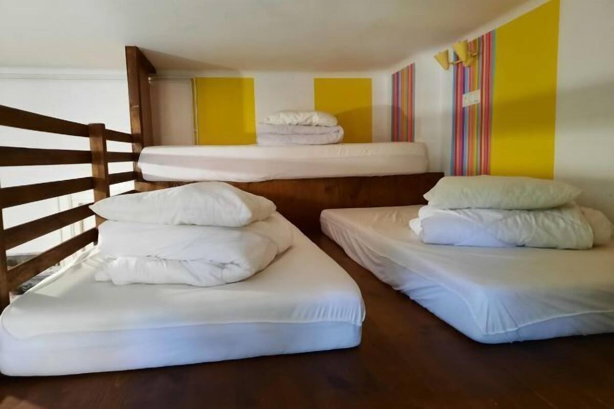 A room with three single beds, wooden headboards, and a striped wall.