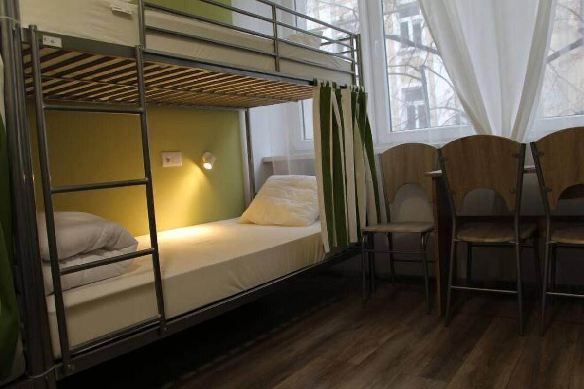 A bunk bed room with a window, a chair, and a light fixture.