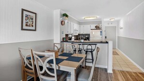 A modern kitchen with white cabinetry, a central island, and a dining area with a table and chairs.