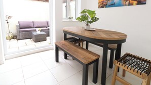 Uma sala de jantar com uma mesa de madeira, bancos e um vaso de planta.