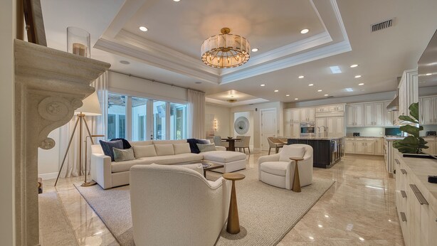Un salón amplio con un sofá seccional grande, un sillón redondo y una mesa de centro. La habitación cuenta con un techo alto con iluminación empotrada y un candelabro.