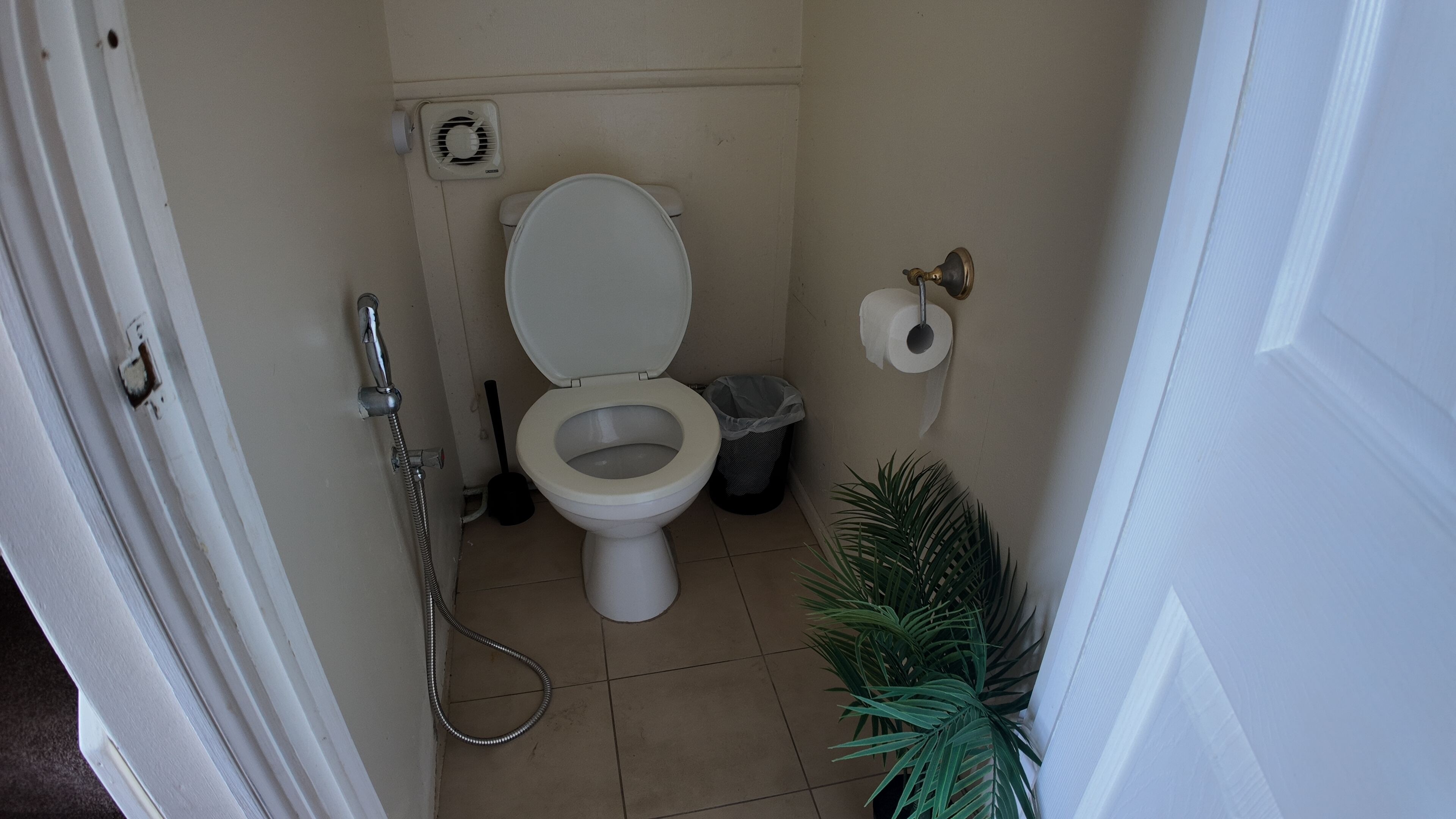 Un baño pequeño con inodoro, ducha y un cesto de basura.