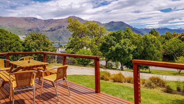 A wooden deck with outdoor furniture overlooking a mountainous landscape.