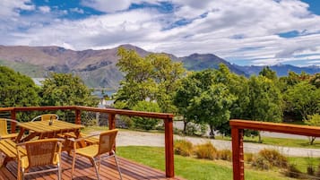 Terraza de madera con mobiliario exterior con vistas a un paisaje montañoso.