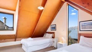 A bedroom with two beds, a window, a radiator, and a picture on the wall.