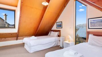Ein Schlafzimmer mit zwei Betten, einem Fenster, einer Heizung und einem Bild an der Wand.