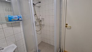 Une salle de bain avec une douche à parois de verre, un lavabo blanc et un distributeur de serviettes.