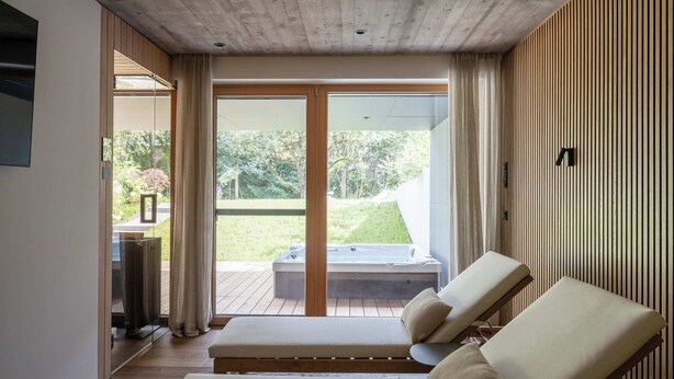 A modern room with a wooden ceiling, a sliding glass door leading to a deck, and two lounge chairs. - Haus Jolanda by we rent (Piesendorf)