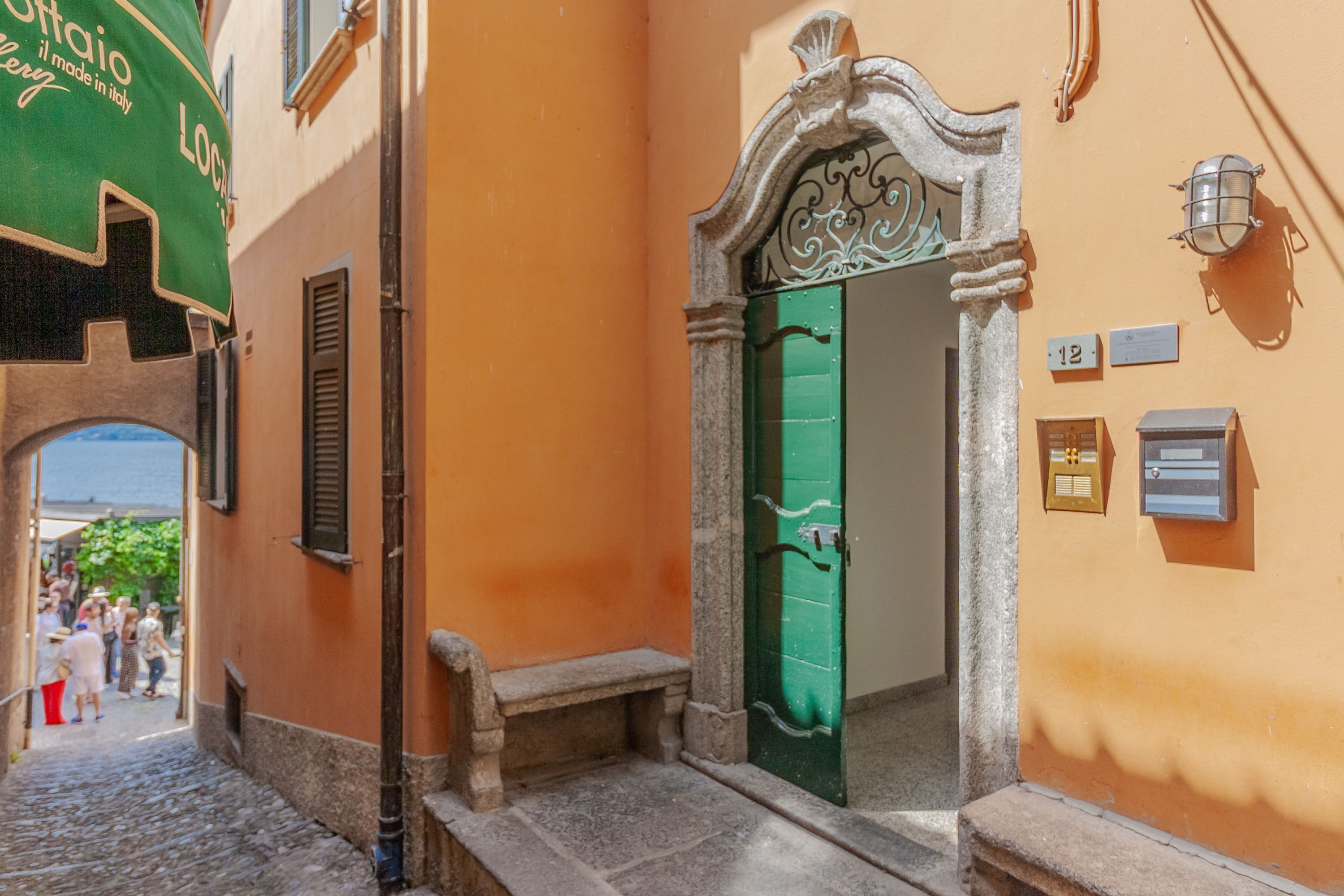 A narrow street with a green door and a stone bench.