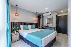 Moderni hotellihuone, jossa on suuri sänky, yöpöydät, peili ja vaatekaappi.