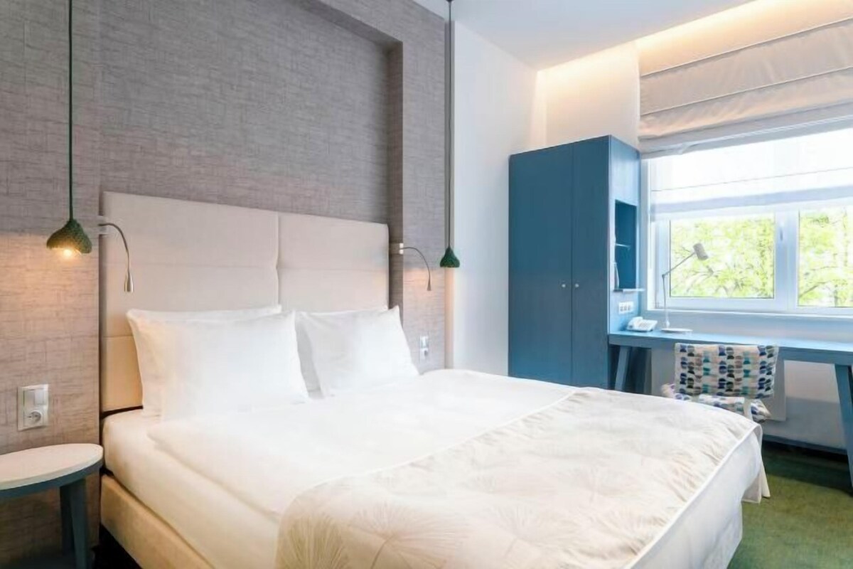 Una habitación de hotel moderna con una cama, un escritorio y una ventana.