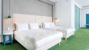 Habitació d'hotel amb dos llits, una catifes verda i una paret decorativa de maó.