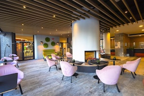 A modern lobby with a central seating area, a fireplace, and a reception desk. - Metropol (Warsaw)