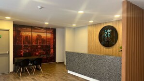 A modern reception area with a cityscape view, a wooden reception desk, and a seating area with chairs. - Modern & Cozy Loft close 93 Park/ Viceroy Park/501 (Bogotá)