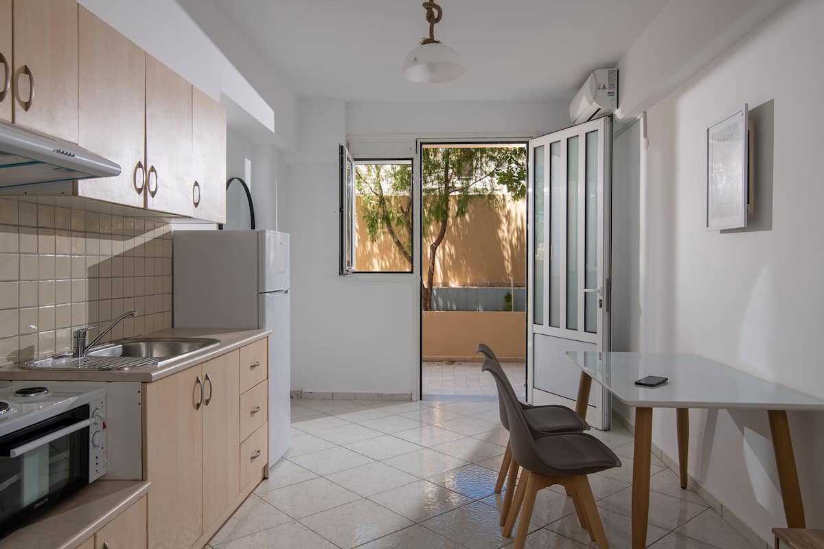 A modern kitchen with a built-in oven, a sink, and a dining area with a table and chairs.