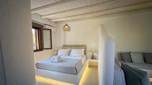 Une chambre à coucher comprenant un lit, des tables de chevet, un luminaire suspendu et un canapé.