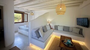 Un salon moderne avec un canapé blanc, une table basse en bois et un luminaire suspendu en fibres tressées.