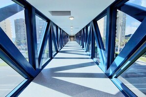 A corridor with a modern design, featuring glass walls and a geometric pattern on the floor.