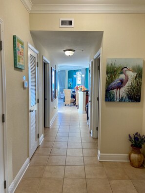 A hallway with a tiled floor, a painting of a bird, and a door on the left.