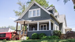 A two-story house with a porch, a staircase, and a fenced yard. - FarnamFieldhouse+HotTub+EpicGameRoom+FirePit+Mural (Omaha)
