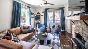 A modern living room with a leather sofa, two armchairs, a coffee table, and a fireplace. - FarnamFieldhouse+HotTub+EpicGameRoom+FirePit+Mural (Omaha)