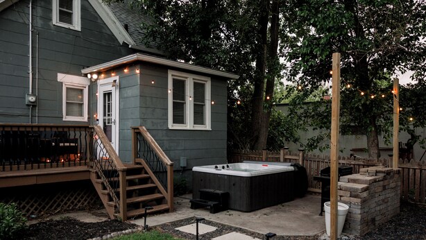 A backyard with a hot tub, wooden deck, and a small house. - FarnamFieldhouse+HotTub+EpicGameRoom+FirePit+Mural (Omaha)