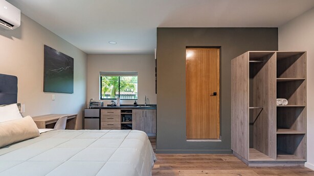 A modern bedroom with a bed, a desk, and a wardrobe. - Lora Loca Inn (El Zonte)