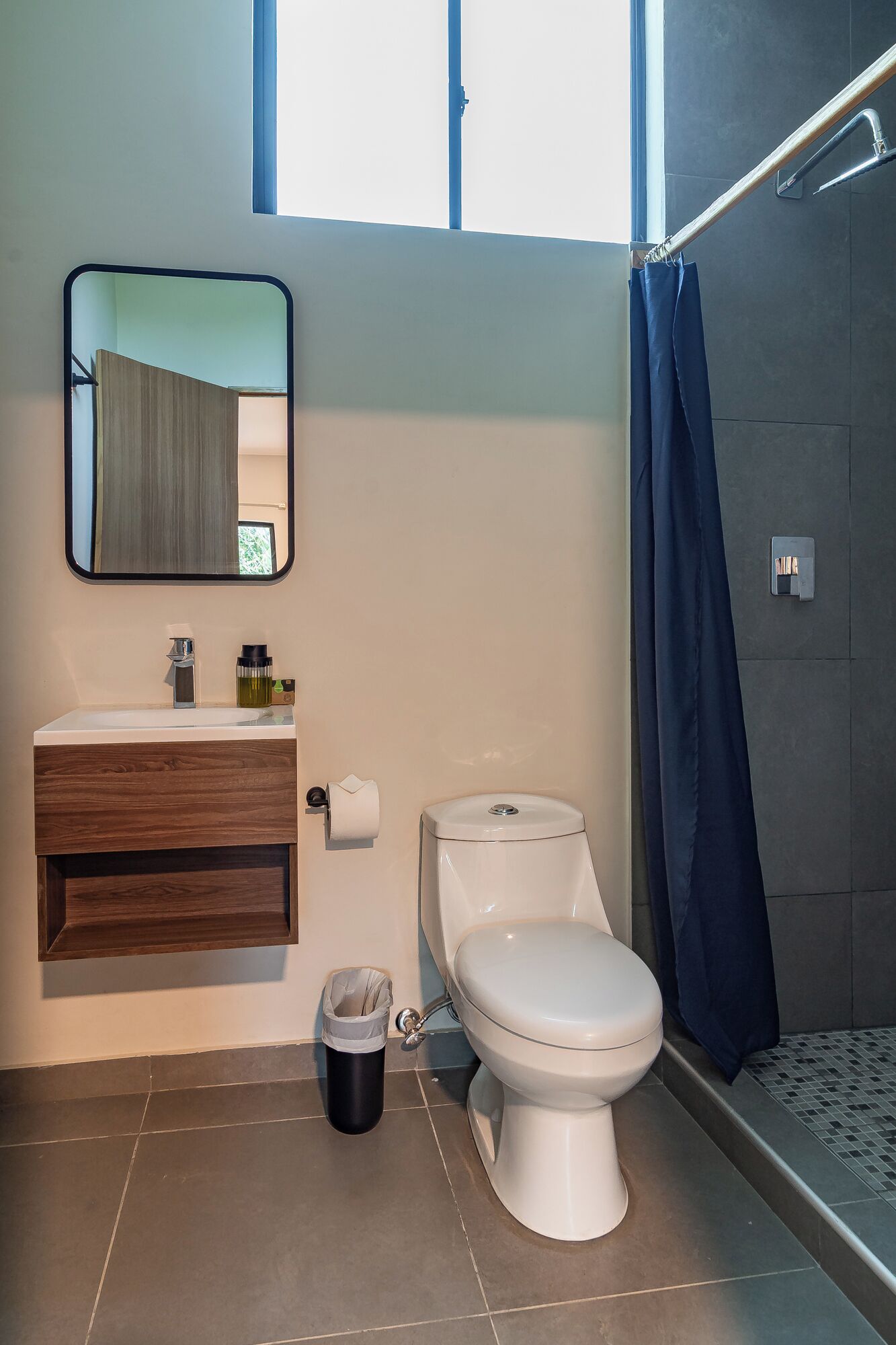 Un baño moderno con inodoro, lavamanos y espejo.