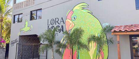 A building with a colorful mural of a bird and the text "LORA LOMA".