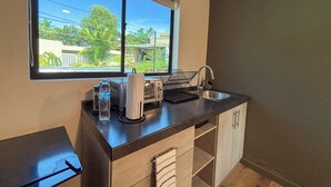 A compact kitchenette with a window, a sink, and a countertop. - Lora Loca Inn (El Zonte)