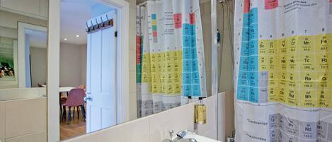 A bathroom with a sink, mirror, and shower curtain displaying the periodic table.