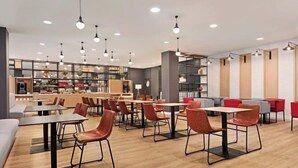 Um café moderno com diversas áreas de estar, incluindo mesas e cadeiras, e um balcão visível com exposição de alimentos.