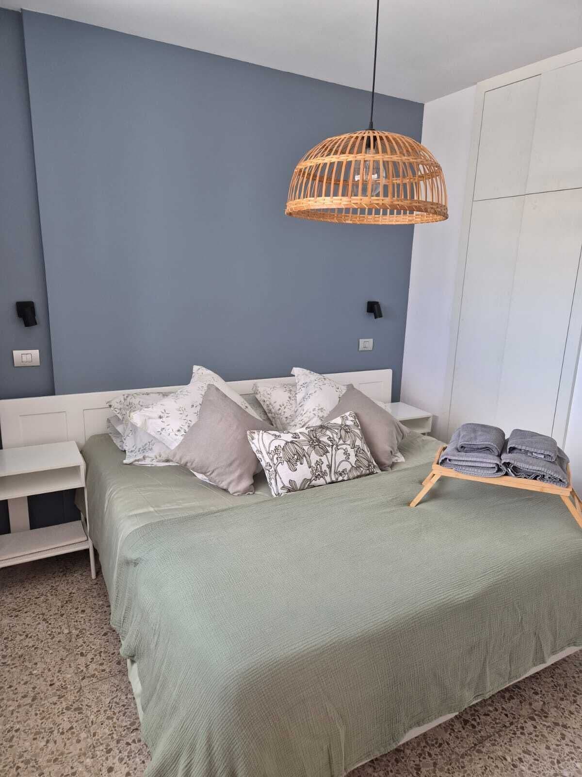 Un dormitorio con una cama, una mesita de noche, una lámpara de pared y un armario.