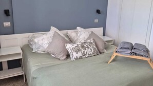 A bedroom with a bed, a bedside table, a wall-mounted lamp, and a wardrobe. - Ocean Terrace Quarries. (Las Palmas de Gran Canaria)