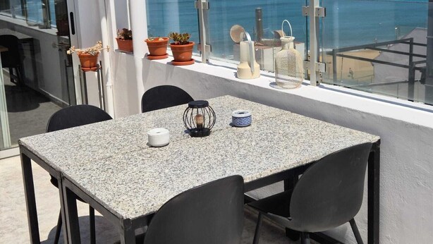 A balcony with a table and chairs, potted plants, and decorative items overlooking the ocean. - Ocean Terrace Quarries. (Las Palmas de Gran Canaria)