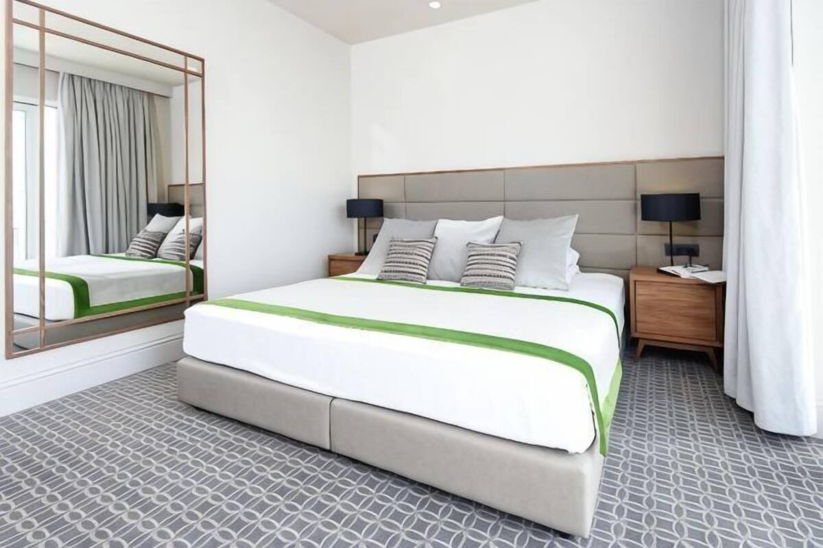 Habitación de hotel con una cama grande, una mesita de noche, un espejo y un piso con diseño.